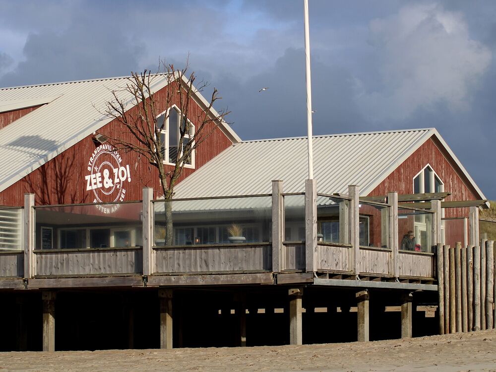 Houten strandpaviljoen op palen aan het strand van Petten met een breed terras
